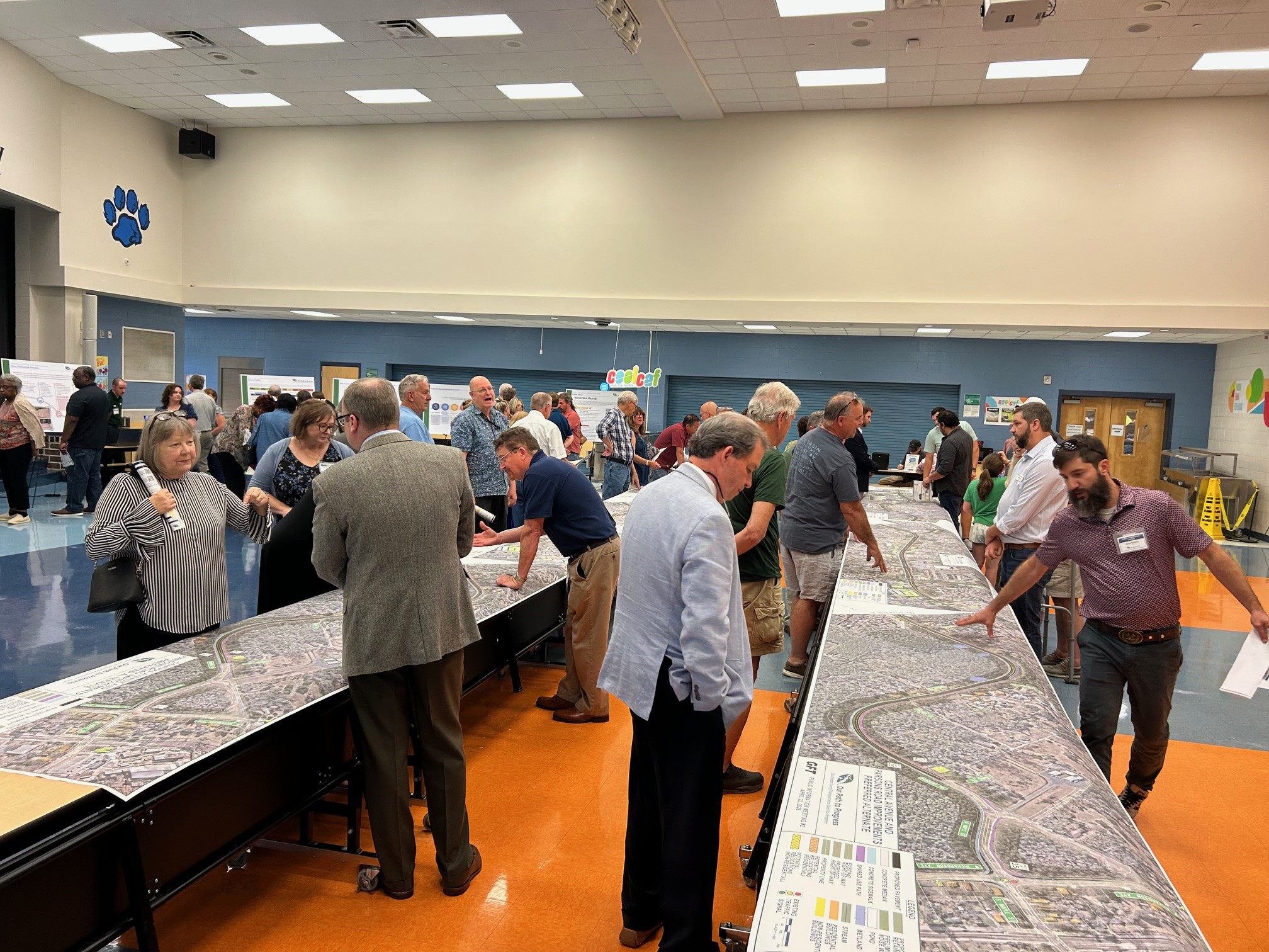 Community members gathered around tables reviewing public meeting materials. 